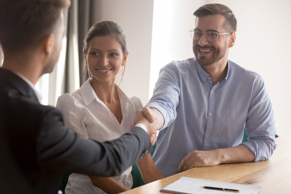 Happy young couple or hr team handshake lawyer job applicant Happy young couple at meeting family shake hand of insurer thanking for consulting buying insurance services